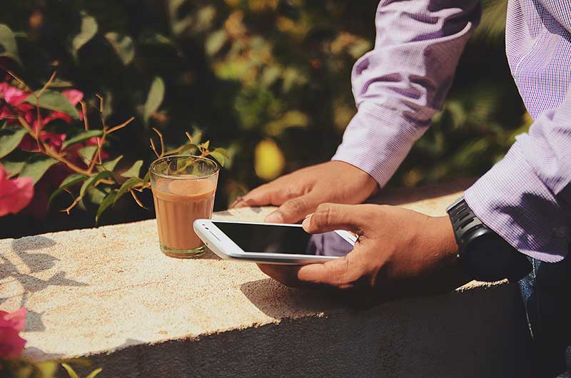 melihat smartphone sambil minum kopi